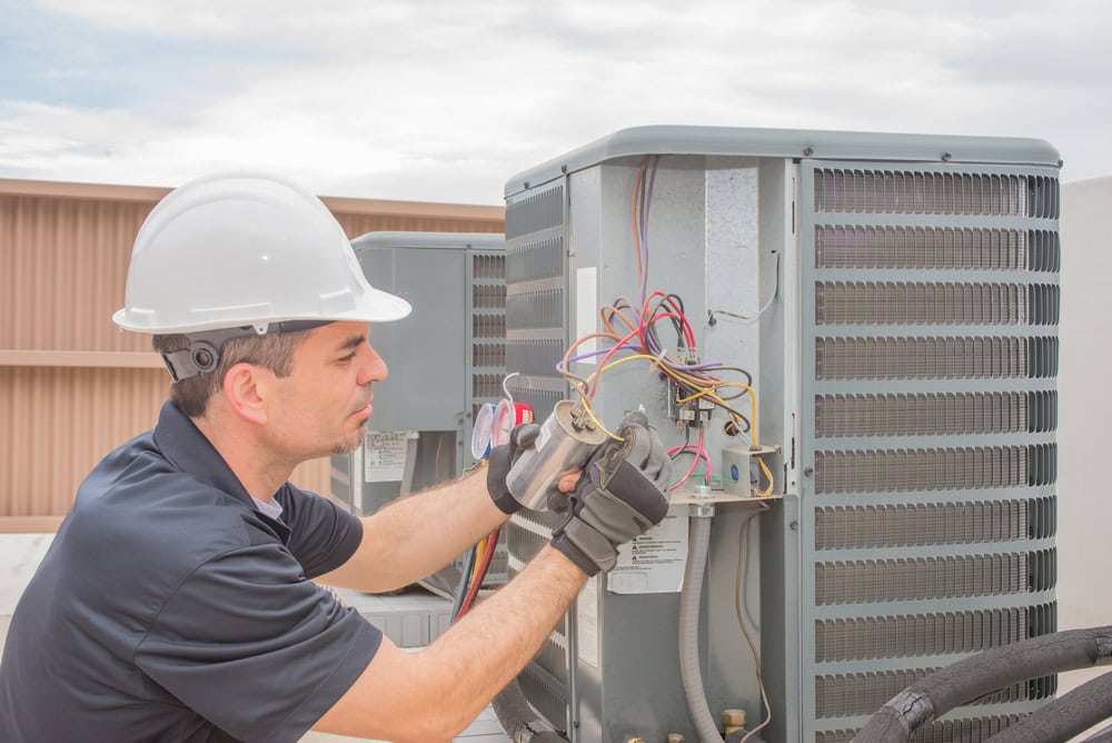 HVAC technician working on a capacitor part of a condensing unit, ensuring optimal performance and efficiency in Fairfield County, CT for Temp Assure Heating