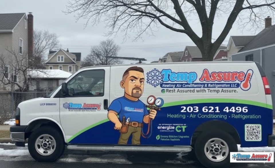 A Temp Assure service van is parked on a residential street. The van features a cartoon technician holding tools and displays the company's name, services, and phone number, along with colorful graphics and logos.